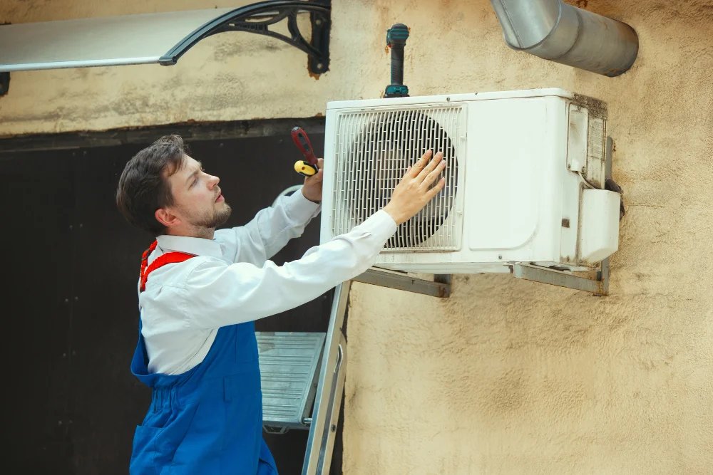 Airco onderhoud Amsterdam met monteur die buitenunit van airco aan gevel installeert