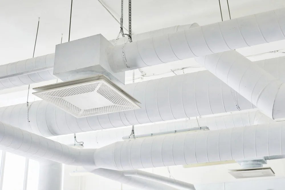 Witte ventilatiekanalen met plafondunit in modern kantoorpand