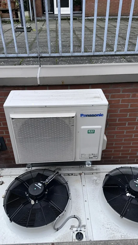 Airco onderhoud Amsterdam met Panasonic airco buitenunit gemonteerd tegen gevel
