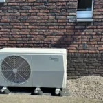 Midea warmtepomp buitenunit geplaatst tegen bakstenen muur