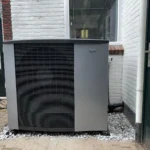 Warmtepomp buitenunit geplaatst bij woning op grind